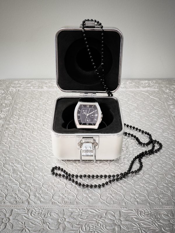 A vertical shot of a beautiful watch in a box with a necklace on it on the table